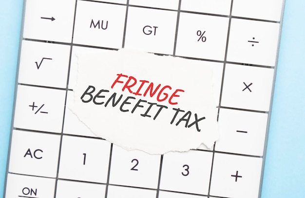 Stylo, calculatrice et lunettes sur fond gris. Notion d'entreprise. Feuille de papier blanc avec FRINGE BENEFIT TAX