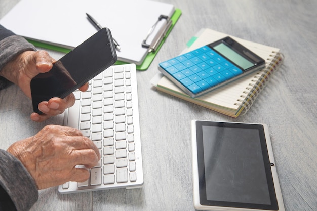 Les mains d'une femme âgée utilisant un smartphone